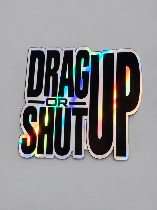 Drag Up or Shut Up sticker with bold black lettering and holographic finish on a gray background