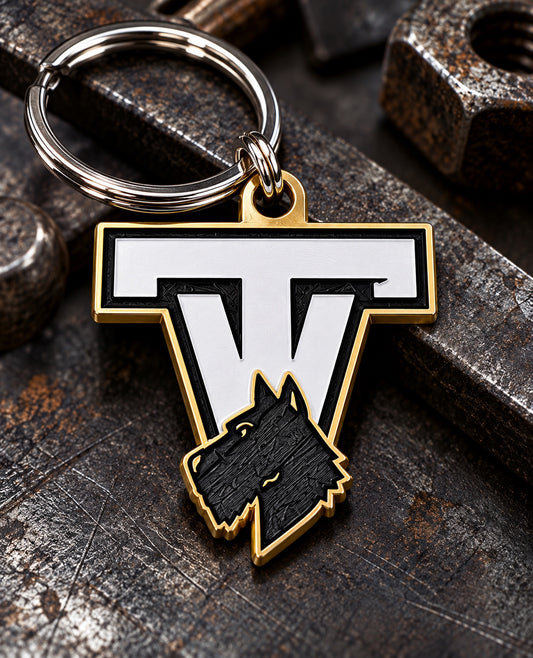 Tri-Valley Scotties TV keychain with black, white, and gold design and silver key ring on a dark industrial background